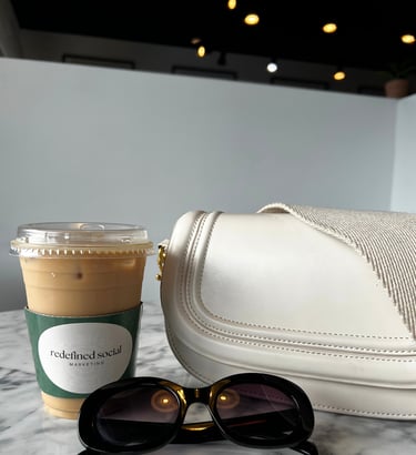 a white purse with sunglasses and a coffee cup