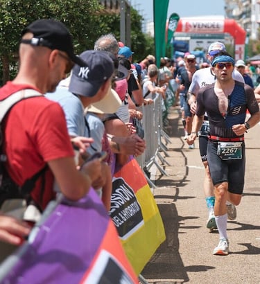 Un jeune homme court sur un triathlon format Ironman il porte des lunettes de soleil et un bandana