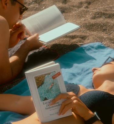 a man and woman reading a book on a blanket