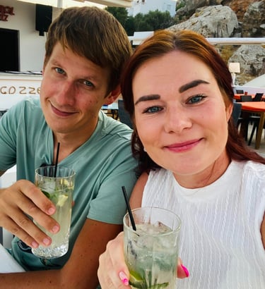 a man and woman sitting at a table with drinks in Rhodes Greece