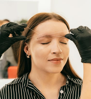 Depilacion de ceja con hilo a cliente en salón de bellezas