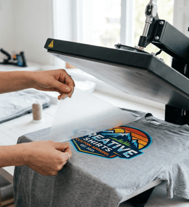 A person applying a custom heat transfer vinyl design to a grey t-shirt using a professional Secabo heat press machine.