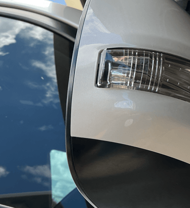 Close-up of a white car side mirror featuring an integrated LED turn signal indicator lamp.