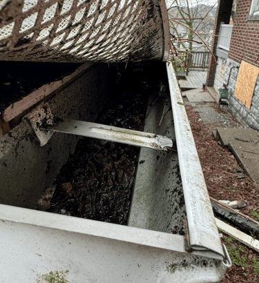 gutter filled with soggy debris due to failed gutter guard system
