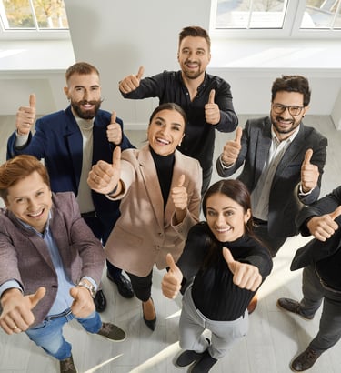 Grupa uśmiechniętych ludzi patrząca w górę i pokazująca kciuk do góry