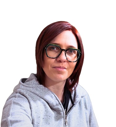 Professional woman with red hair wearing stylish green-rimmed glasses and a grey hoodie.