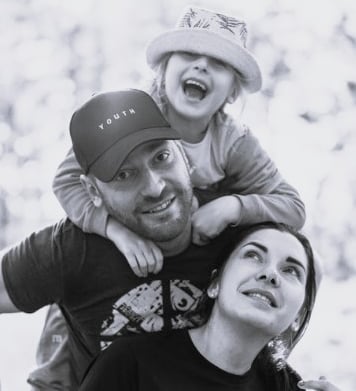 a picture of a father, mother and child who is piggy backing on the father's back smiling