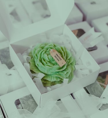 Vela artesanal de rosa verde en una caja blanca con una etiqueta personalizada para recuerdos