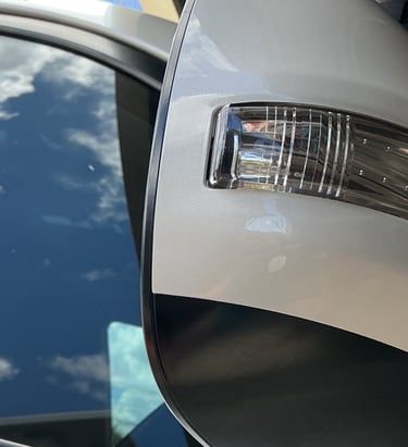 Close-up of a white car side mirror featuring an integrated LED turn signal indicator lamp.