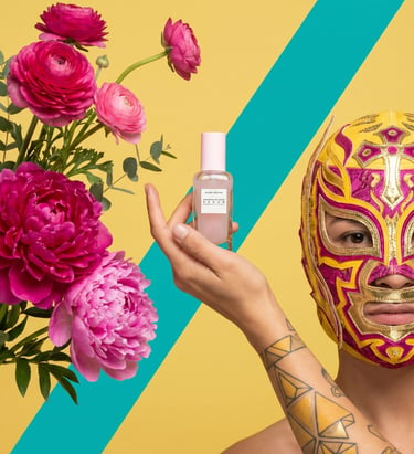 A person in a lucha libre mask holding Glow Recipe Dew Drops serum next to pink peonies.