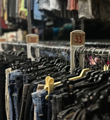 a bunch of clothes hanging on a rack in a warehouse of rental costumes