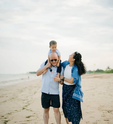 Parents embracing their son during a relaxed family photography session at Nusa Dua Beach Bali