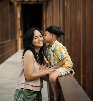 Mother and son sharing a quiet moment on a wooden bridge during a family photography session at The Meru Sanur Bali