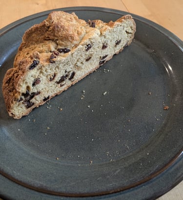 A rough textured raisin-studded loaf of bread, cut open to show texture
