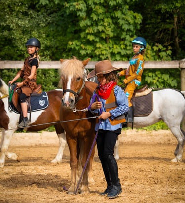 a group of people riding horses in a dirt field and a boy dressed like cowboy