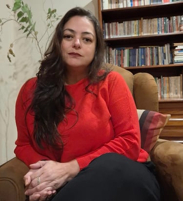 Psicóloga Marcia Lhamas em seu espaço de atendimento online, cercada por plantas e livros, em atmosf