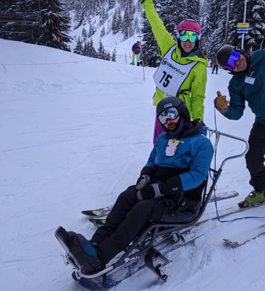 alt="Sean in his sit ski with Outdoors for All instructors Kristin and Ted, posing for the camera