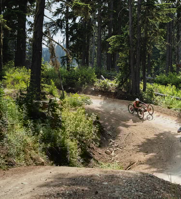 Two adaptive mountain bike riders make their way down the berms of the Whistler Mountain Bike Park.