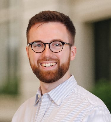 a man with a beard and glasses on a city street