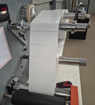 Maquina rebobinadeira com um rolo de etiqueta branca.