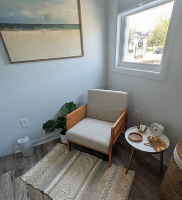 a waiting area with a chair and a table with a painting on the wall