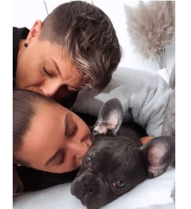 a man and woman cuddling up to a puppy