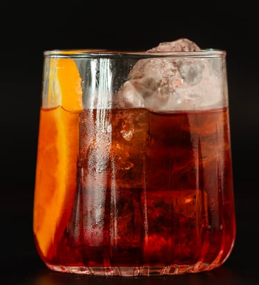 Klassischer Negroni-Cocktail mit Gin, Wermut und Bitterlikör, serviert auf Eis mit einer Orangensche