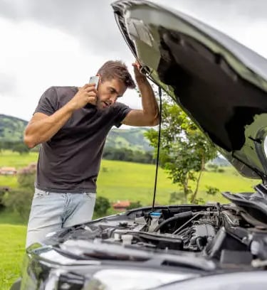 a man is talking on the phone while he is looking at the car