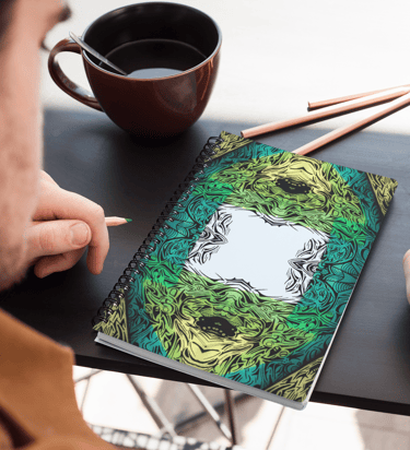 a man is sitting at a table with a notebook and a cup of coffee