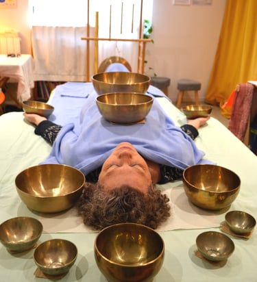 Une femme pendant une séance de sonothérapie entourée de bols chantants.
