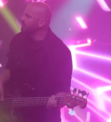a man with a guitar and a guitar in front of a purple light