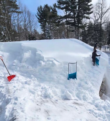 Professional roof snow removal with shovels on a house after a heavy winter storm.