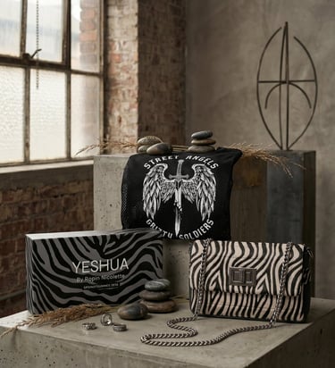 YESHUA by Robin Nicolette zebra print handbag and gift box displayed on industrial stone blocks.