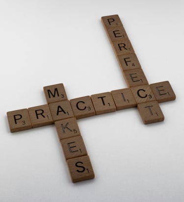 Wooden letter tiles arranged to spell Practice Makes Perfect on a white surface.