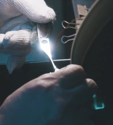 Proceso de afilado de tijeras de peluquería profesionales realizado por artesano en rueda de amolar.