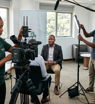 Professional film crew filming a corporate interview with lighting, boom mic, and high-end video camera.