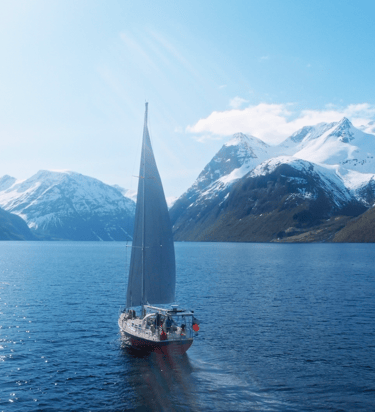a sailboat sailing on a fjord with mountains in the background | ski and sail in the Lyngen Alps