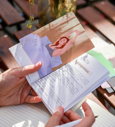 Kortelė iš "Terapiniai pokalbiai su savimi" rinkinio padėta ant knygelės, laikomos rankose