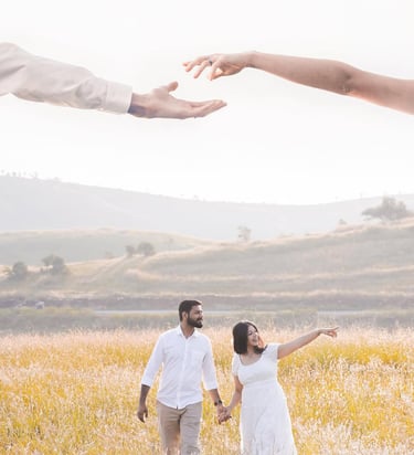 Couple holding hands in a sunlit meadow during an outdoor engagement photoshoot.