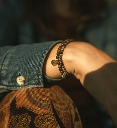 pulsera de cuentas oscuras y pequeño dije dorado.