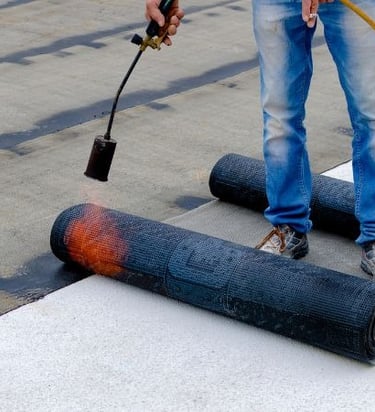 a man is using a hose to remove a black paint on a concrete floor