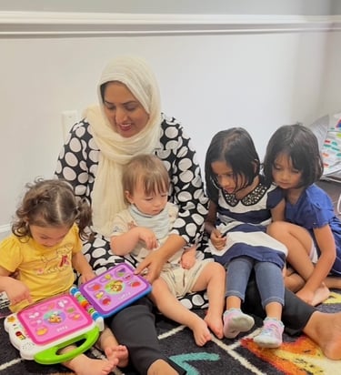 Daycare provider with children sitting together and reading an electronic book