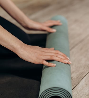 Hände, die eine Yogamatte aufrollen