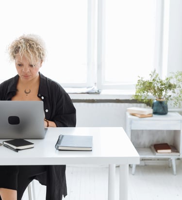 Person working on a laptop with a notebook and coffee, creating digital product ideas for beginners.