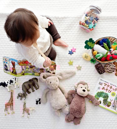 a little girl sitting on a blanket with toys
