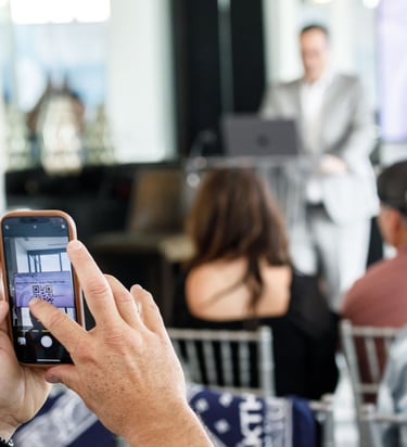 a man is taking a photo of a speaker at a business meeting