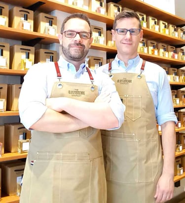 Kvepalų kūrėjai iš Valensijos, o už jų – lentyna pilna įvairių nišinių, jų kurtų kvepalų.