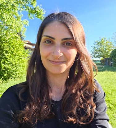 Donna in primo piano che sorride con sfondo di prato e cielo