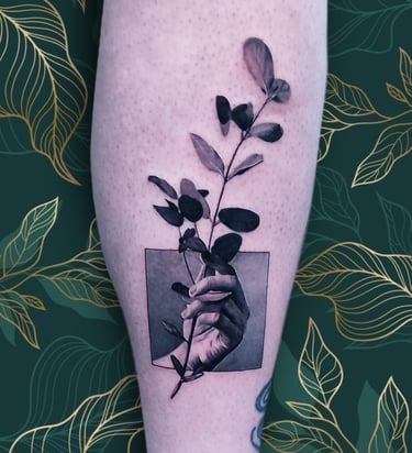 a person's hand holding a plant with leaves. custom piece by Katarsis Tattoo Perú.
