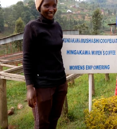 a woman standing in front of a sign that says, women"s coffee famers